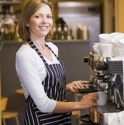 Woman making coffee in restaurant smiling