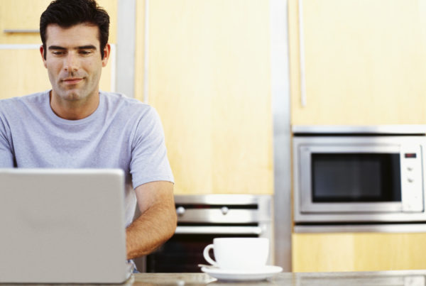 man working on his laptop in the kitchen
