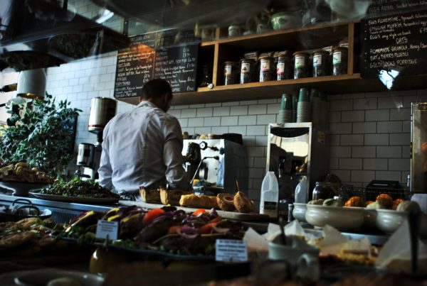 cafe with fresh produce and a worker making a coffee