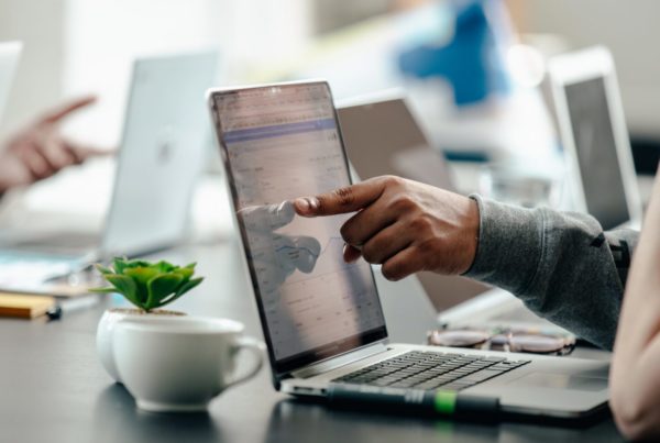 someone pointing at something on a laptop screen
