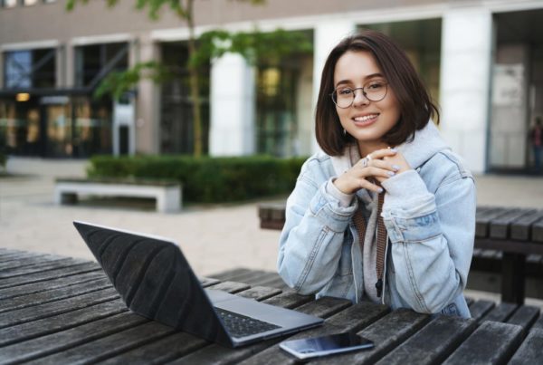 woman working outside on a picnic bench with her laptop