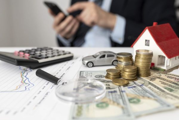 cash, toy car and toy house on desk with a calculator and a man working