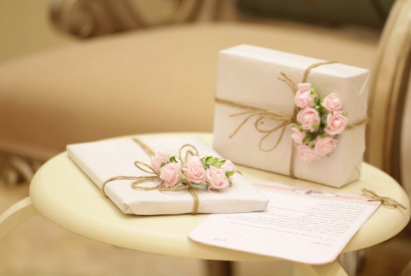2 gifts wrapped in white wrapping paper and accessorised with pink flowers