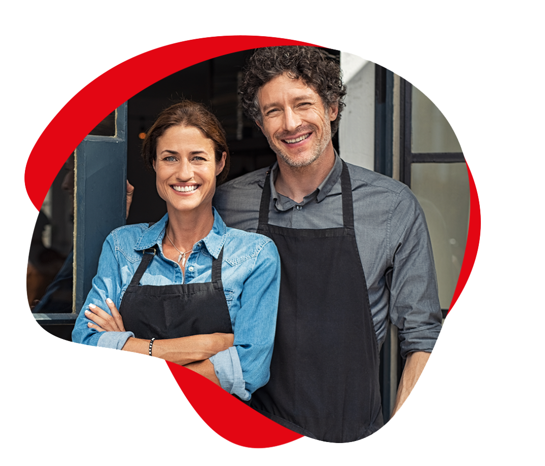 smiling man and woman in aprons in front of a shop door posing