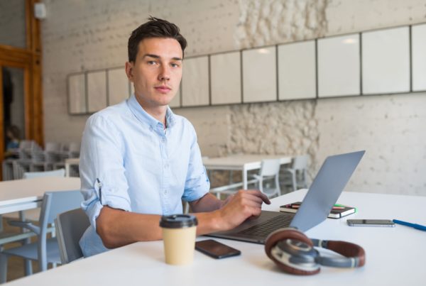man sitting in an open office space working on his laptop